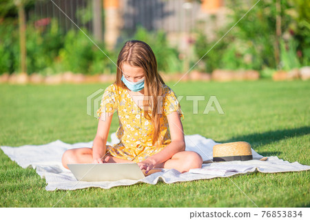 Little girl outdoors in the park with computer Little girl outdoors in the park with computer 76853834