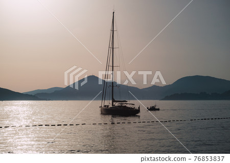 Sailing yacht sails on the sea against the background of mountains in the evening Sailing yacht sails on the sea against the background of mountains in the evening 76853837