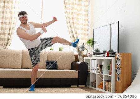 Fat man in sportswear and dumbbells does physical exercise 76854086