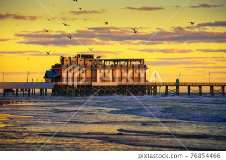 Sunrise above Daytona Beach Main Street Pier, Florida, with a flock of seagulls 76854466