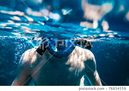 Man in snorkeling mask underwater swimming Man in snorkeling mask underwater swimming 76854559