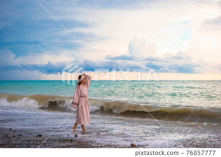 Woman on the beach enjoying summer holidays looking at the sea 76857777