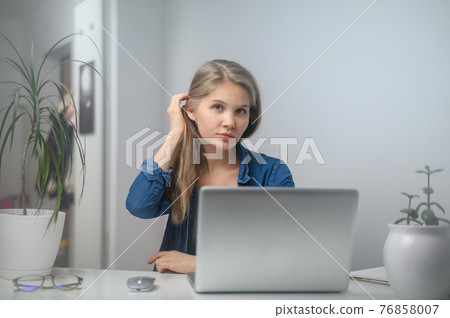 A girl with a laptop is studying at an online school. White room background 76858007