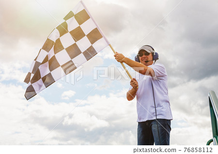 Man waves a checkered flag Man waves a checkered flag 76858112
