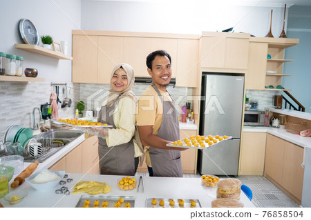 muslim man and woman with baking tray of nastar snack looking at camera smiling muslim man and woman with baking tray of nastar snack looking at camera smiling 76858504