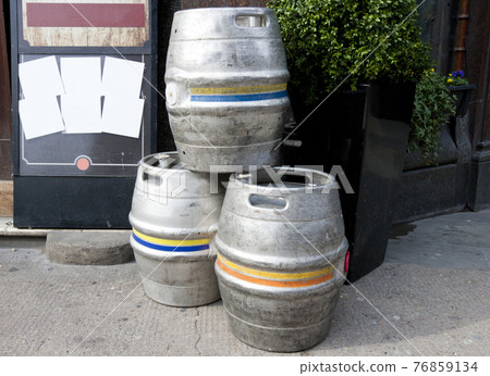 Three empty metal kegs outside a bar Three empty metal kegs outside a bar 76859134