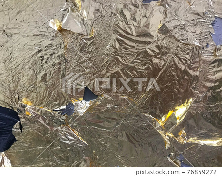 Shiny torn and wrinkled golden foil texture. Crumpled metal background 76859272
