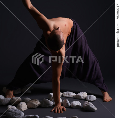 Man doing yoga white stones on the floor 76860047