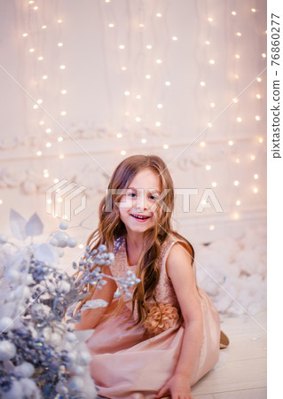 Portrait of a little girl with curly hair on Christmas Eve, the New Year will bring gifts. 76860277