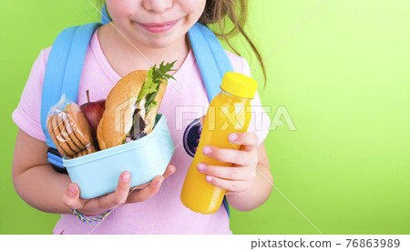 Young schoolgirl with lunch box on a green background. Little girl with a school backpack and a set Young schoolgirl with lunch box on a green background. Little girl with a school backpack and a set 76863989
