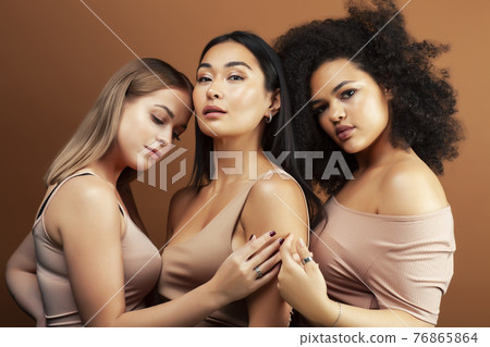 young pretty asian, caucasian, afro woman posing cheerful together on brown background, lifestyle diverse nationality people concept young pretty asian, caucasian, afro woman posing cheerful together on brown background, lifestyle diverse nationality people concept 76865864