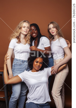 young pretty caucasian, afro, scandinavian woman posing cheerful together on brown background, lifestyle diverse nationality people concept 76866126