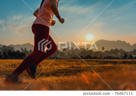 Asian woman enjoys running outside with beautiful summer evening in the countryside. Asian woman enjoys running outside with beautiful summer evening in the countryside. 76867113