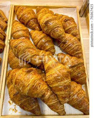 Vertical photo of many French croissants on wood tray Vertical photo of many French croissants on wood tray 76867425