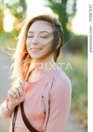 Portrait of young caucasian girl standing outside with closed eyes. 76867835