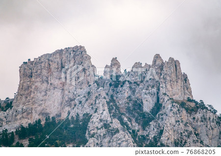 High rocky mountains with forested slopes and peaks hidden in the clouds. Ai-Petri, Crimea 76868205