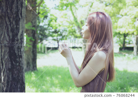 Portrait of a beautiful woman blowing dandelion fluff 76868244