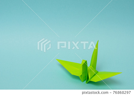 Yellow-green paper cranes on a light blue background 76868297