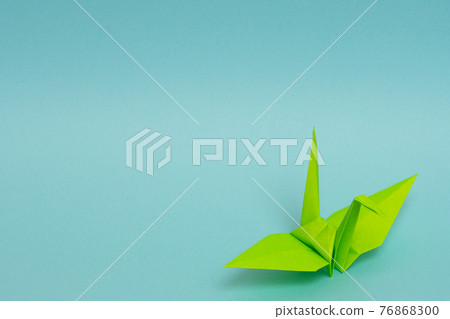 Yellow-green paper cranes on a light blue background 76868300
