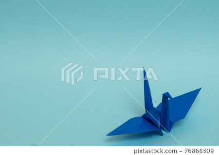 Blue paper crane on a light blue background Blue paper crane on a light blue background 76868309