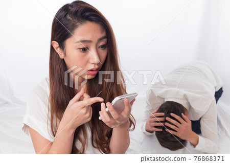 一個男人用智能手機對著一個女人抱頭 76868371