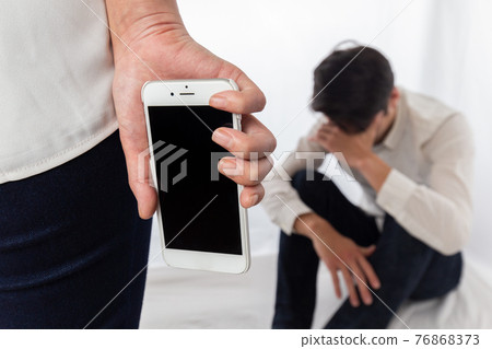 一個男人用智能手機對著一個女人抱頭 76868373