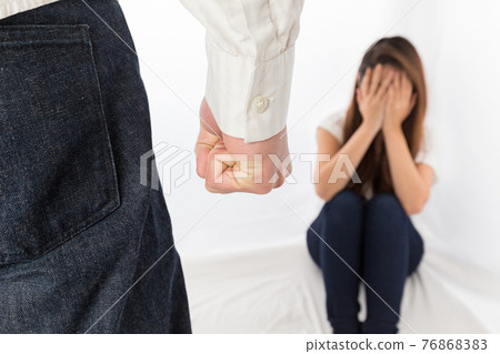 A woman frightened by a man holding a fist A woman frightened by a man holding a fist 76868383
