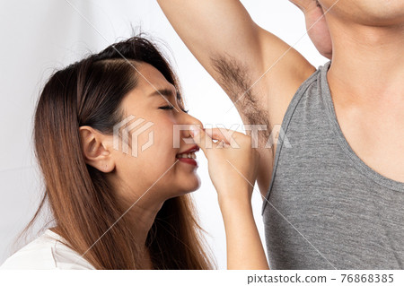A woman pinching her nose to the odor beside a man A woman pinching her nose to the odor beside a man 76868385