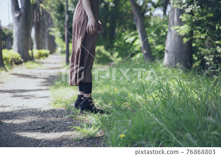 Portrait of a beautiful woman standing on a tree path 76868803