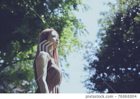 站立在樹道路的一名美麗的婦女的畫象 76868804