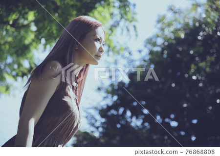 Portrait of a beautiful woman standing on a tree path 76868808