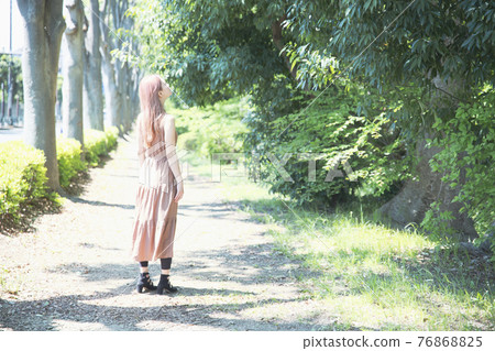 Portrait of a beautiful woman standing on a tree path Portrait of a beautiful woman standing on a tree path 76868825