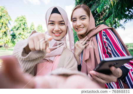muslim woman in head scarf meet friends and using phone in the park muslim woman in head scarf meet friends and using phone in the park 76868831