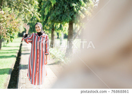 Muslim women in hijabs outdoors on sunny day with friend happy 76868861