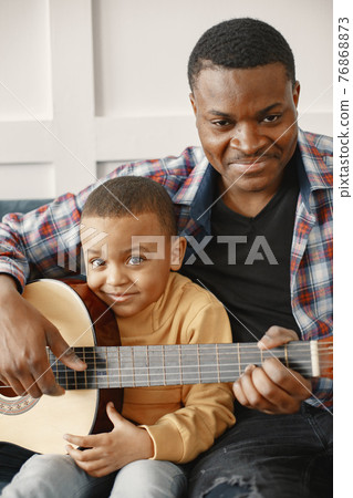 Father teaches his son to play guitar 76868873