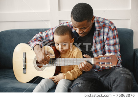 Father teaches his son to play guitar 76868876
