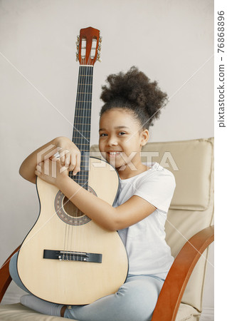 Little girl with a guitar on a chair Little girl with a guitar on a chair 76868896