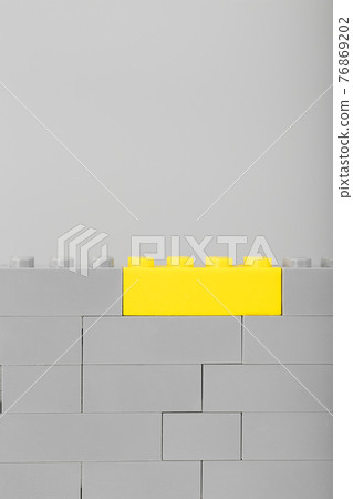 A gray wall made of a toy construction set with the last yellow brick A gray wall made of a toy construction set with the last yellow brick 76869202
