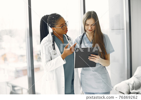 Two female doctors looking at an document 76869262