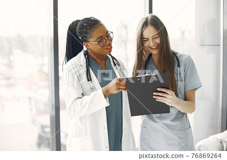 Two female doctors looking at an document Two female doctors looking at an document 76869264
