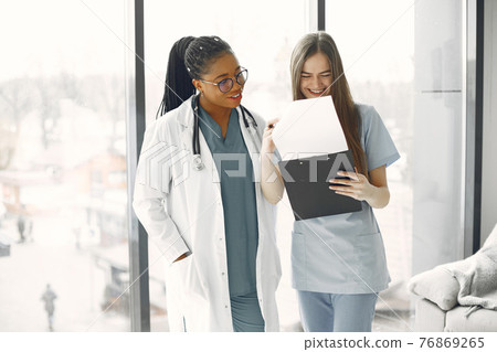 Two female doctors looking at an document Two female doctors looking at an document 76869265