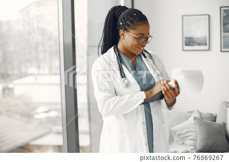 African doctor standing by window with a folder 76869267
