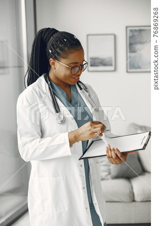 African doctor standing by window with a folder African doctor standing by window with a folder 76869268