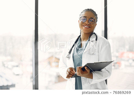 African doctor standing by window with a folder African doctor standing by window with a folder 76869269