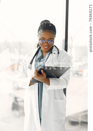 African doctor standing by window with a folder African doctor standing by window with a folder 76869271
