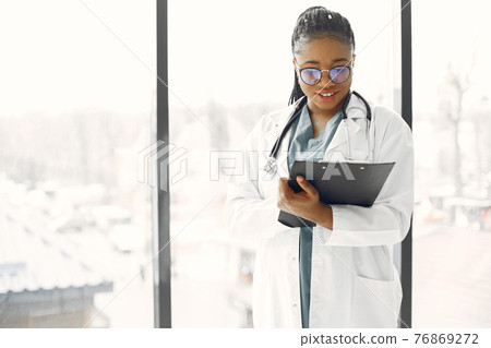 African doctor standing by window with a folder African doctor standing by window with a folder 76869272