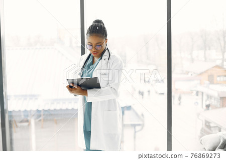 African doctor standing by window with a folder 76869273