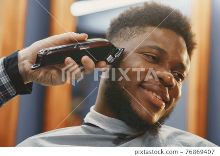 Young African-american man visiting barbershop Young African-american man visiting barbershop 76869407