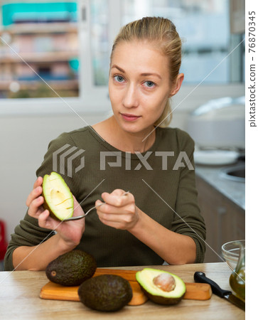 Happy housewife cooking with avocado at home kitchen Happy housewife cooking with avocado at home kitchen 76870345