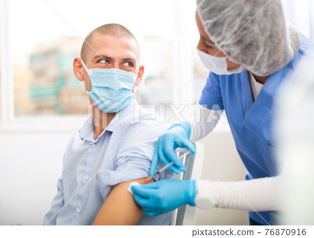 doctor in a protective face mask makes vaccination doctor in a protective face mask makes vaccination 76870916